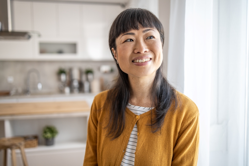 Une femme est dans sa maison et elle sourit en pensant à sa retraite anticipée.